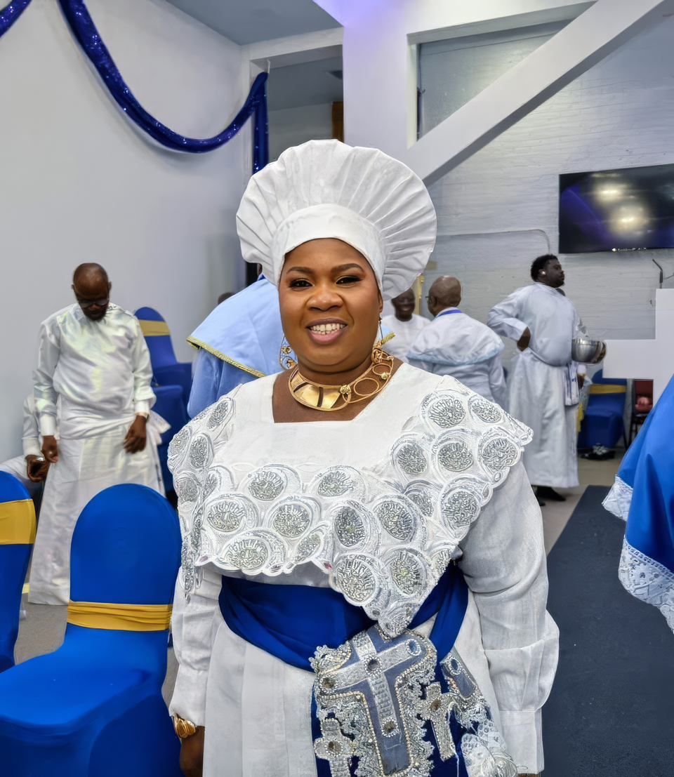 A smiling parish member in a white cap and embroidered white garment with a blue sash during the celebration.